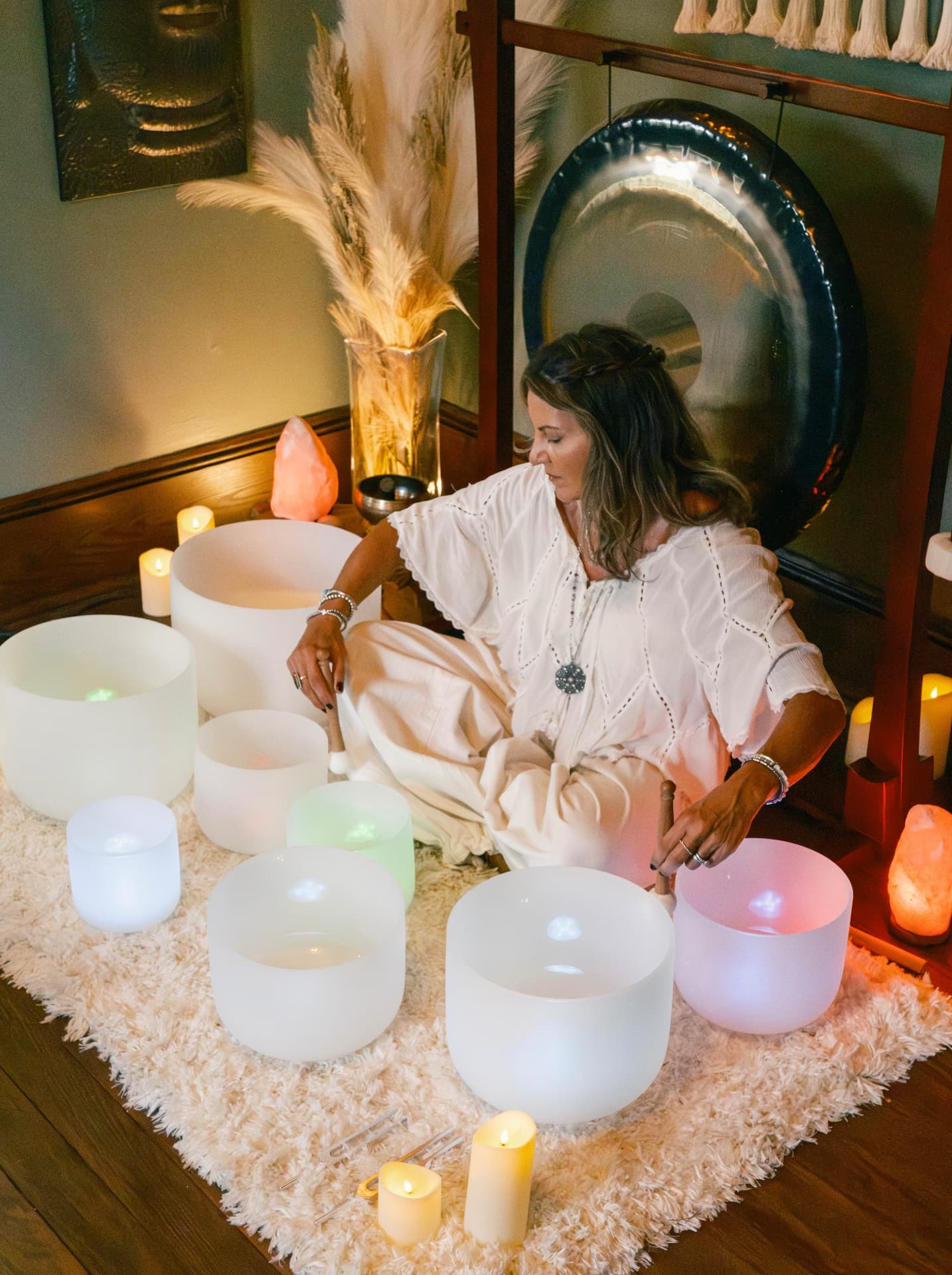 Tanya playing crystal singing bowls by candlelight in the Sound & Soul studio